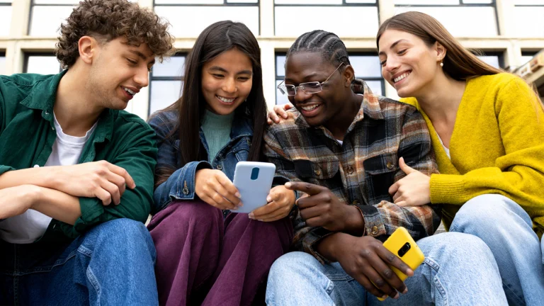 4 people sitting and looking at a phone